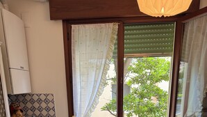 A compact kitchen with a dining table and chairs, a washing machine, and a window with a view of greenery. - VENICE LIDO, SEA AND CINEMA<br>...  (Venezia)