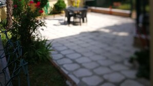 A patio area with a table and chairs, surrounded by greenery and a building in the background. - VENICE LIDO, SEA AND CINEMA<br>...  (Venezia)