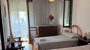 A bedroom with two beds, a wooden desk, a chair, a dresser, and a hanging light fixture. - VENICE LIDO, SEA AND CINEMA<br>...  (Venezia)