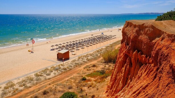 Une plage offrant une vue dégagée sur l’océan, une rive sablonneuse et une falaise rocheuse.