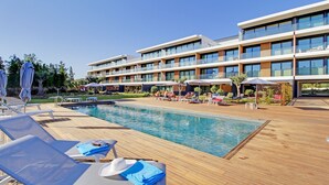 Un hôtel moderne doté d’une piscine, de chaises longues et de parasols.