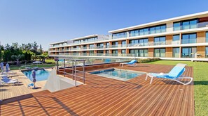 A modern hotel with a rooftop pool area, including lounge chairs and a glass balustrade.