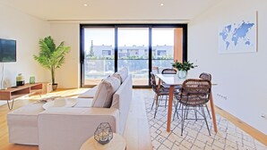Un salon moderne avec un canapé, une table à manger, des chaises et une grande fenêtre.
