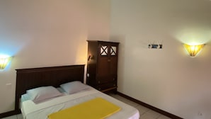 A bedroom with a bed, a wooden wardrobe, and two wall-mounted light fixtures.