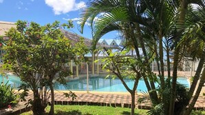 A swimming pool surrounded by lush greenery and a fenced area.