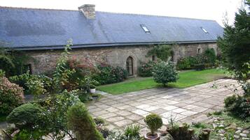 Experience a tranquil retreat in this charming country house with a central arched doorway and lush garden surroundings.