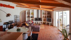 A spacious living room with a high ceiling, a fireplace, a television, and a dining area with a table and chairs. - (10PAX) Peace bellow a starred sky with special views to olives and cork tree (Evoramonte)