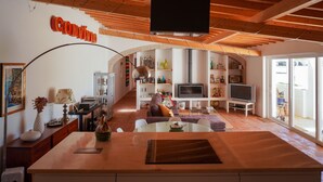 A spacious living area with a kitchen, dining area, and a TV mounted on the ceiling. - (10PAX) Peace bellow a starred sky with special views to olives and cork tree (Evoramonte)