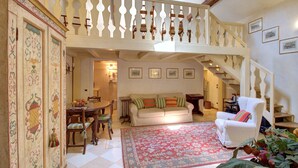 A spacious living room with a high ceiling, a staircase, and a dining area. - MOCENIGO aperitif (Venezia)
