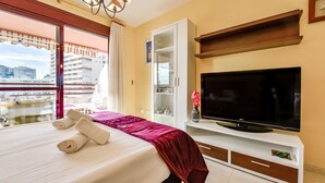Una camera d'albergo con un letto, una televisione, un minibar e vista sugli edifici attraverso una finestra.