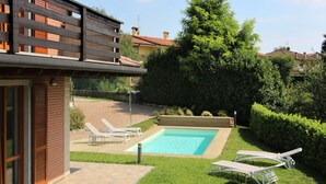 A residential backyard with a swimming pool, two lounge chairs, and a well-maintained lawn. - MAISON LA VALLETTA VILLA WITH POOL BERGAMO  (Ponteranica)