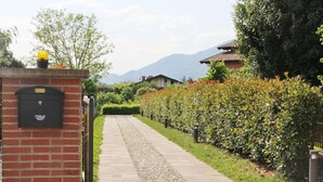 A pathway leading to a building with a brick wall on the left. - MAISON LA VALLETTA VILLA WITH POOL BERGAMO  (Ponteranica)