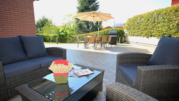 An outdoor patio with wicker furniture, a glass coffee table, and a magazine. - MAISON LA VALLETTA VILLA WITH POOL BERGAMO  (Ponteranica)