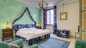 Um quarto com cama de dossel, mesa de cabeceira com abajur, cômoda e janela com cortinas.