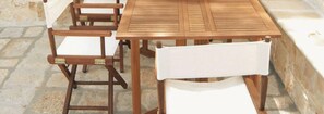 A wooden table with chairs, a stone wall, and a stone floor.