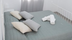 A bedroom with a bed, pillows, a blanket, and a window with curtains.