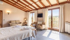 A hotel room with a bed, a sofa, a TV, and a balcony with curtains.