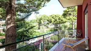 Un balcón con vista a un jardín y coches aparcados.