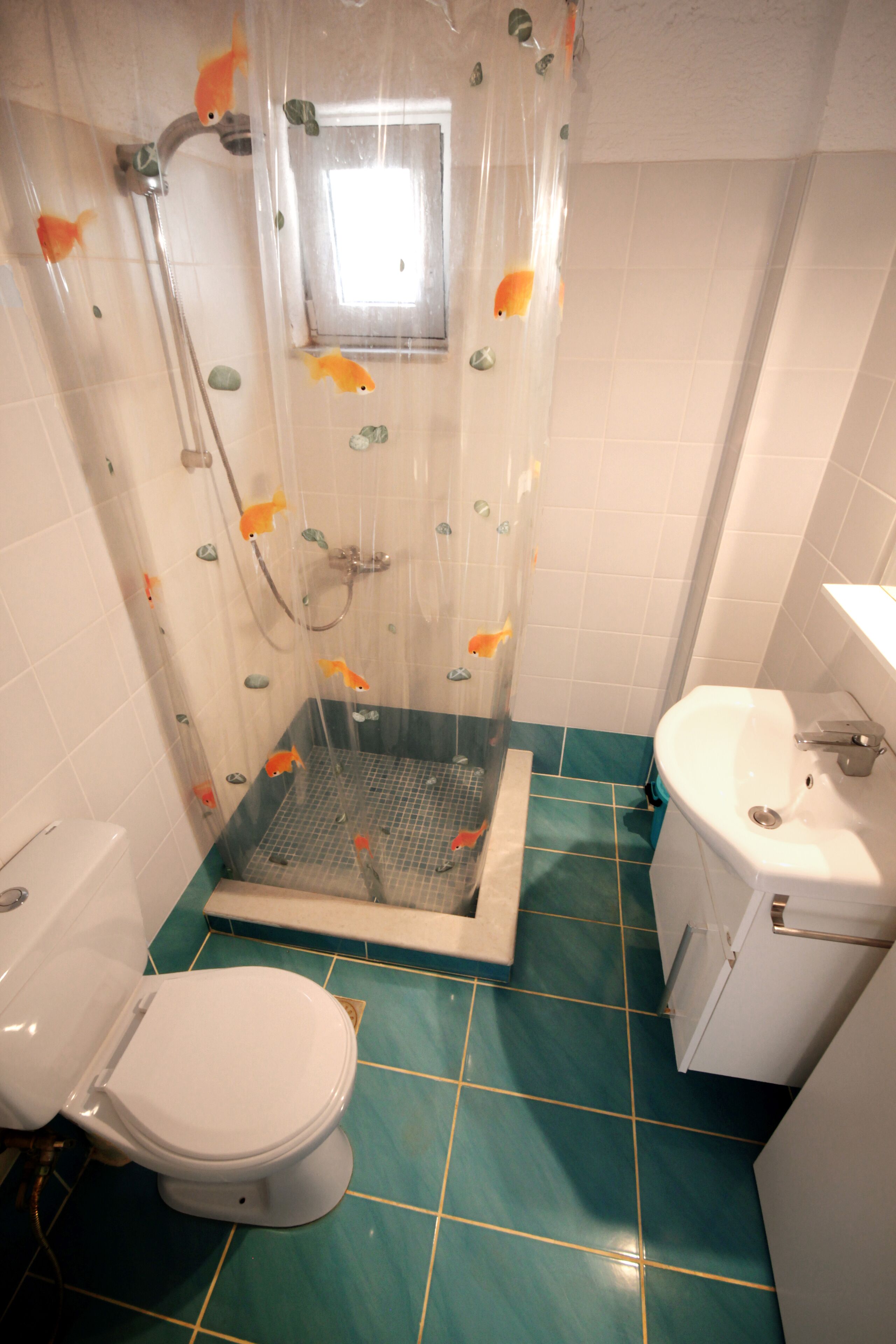 A bathroom with a shower, toilet, and sink.