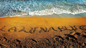 Ein Strand mit Fußspuren und dem Wort 'LAZARUS' im Sand geschrieben.
