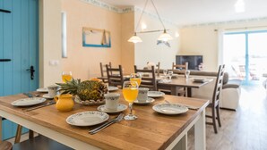 A dining area with a wooden table set for breakfast, including plates, cups, and a pineapple.
