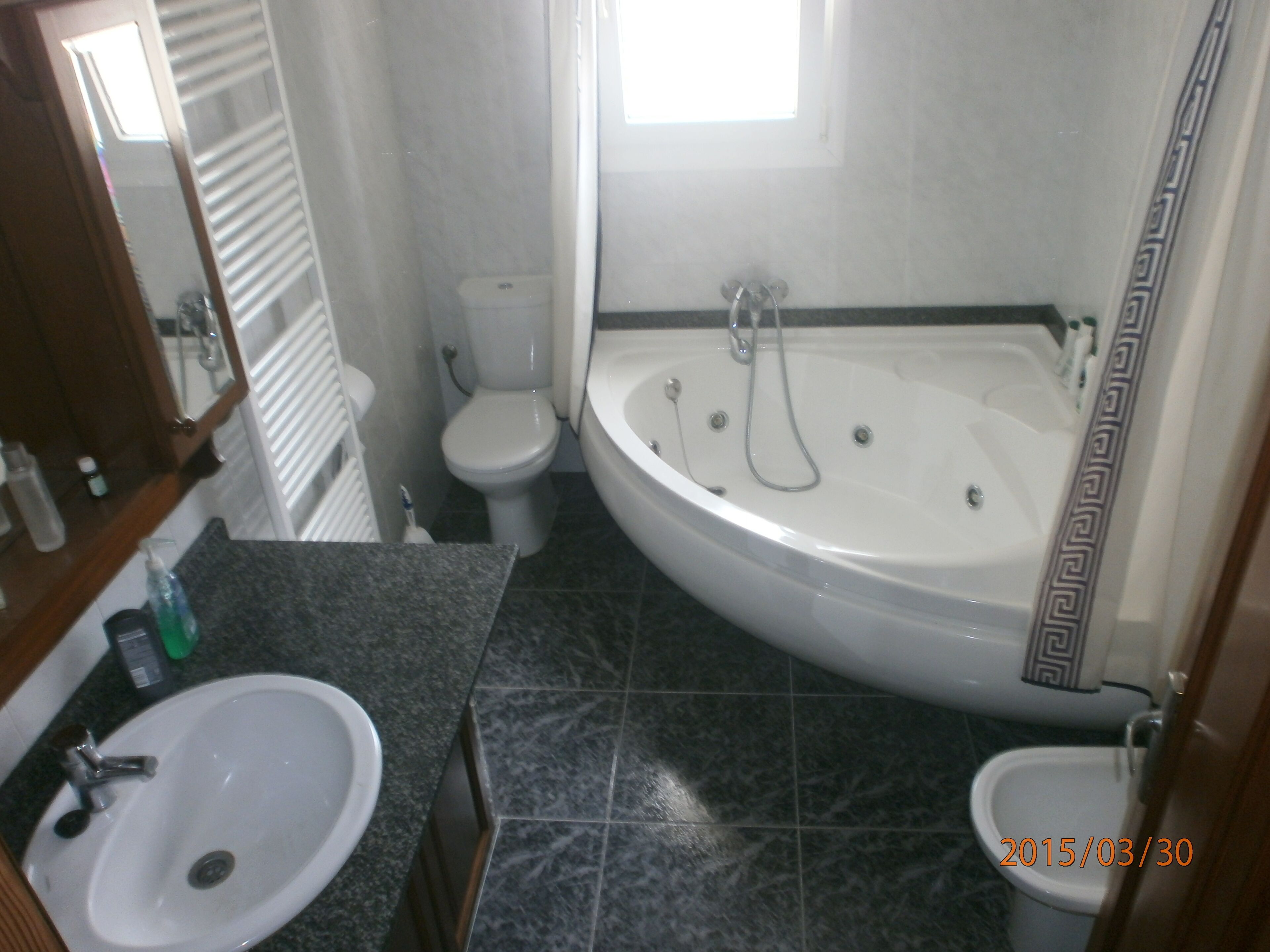 A bathroom with a bathtub, toilet, sink, and a mirror.