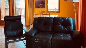 Una habitación con un sofá de cuero negro, una silla de madera y una lámpara de pie.