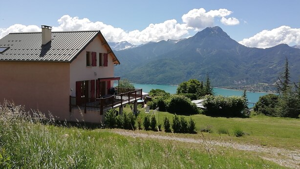 Una casa con balcón que da a un lago y montañas.