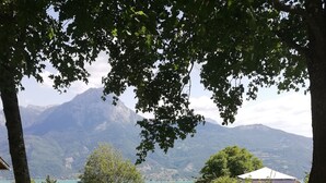 Una mesa de picnic y un banco en un jardín exuberante, con vista a la montaña.