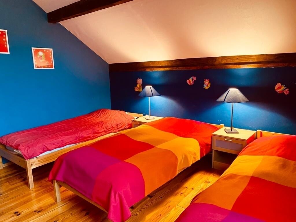 Une chambre avec deux lits, un plancher en bois et un plafond en pente.
