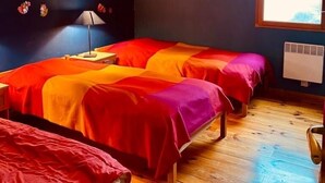 Una habitación con dos camas, suelo de madera, una ventana y un radiador.