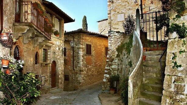 Un estrecho callejón empedrado con una escalera que sube a un edificio.