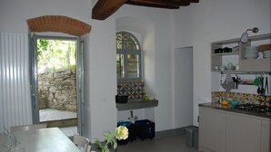 Una cocina con pared de piedra, salpicadero de azulejos y zona de comedor con mesa y sillas.