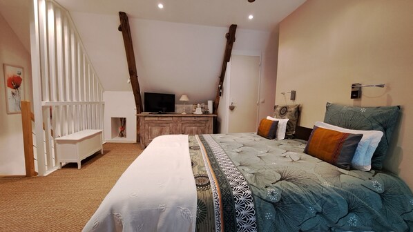 Un dormitorio con cama, escritorio, televisión y ventana con cortinas.