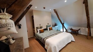 A bedroom with a large bed, a wooden chair, a small table, and a wardrobe.