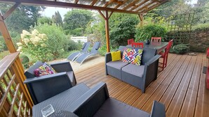 A covered outdoor seating area with wicker furniture and a wooden deck.