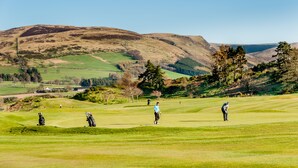 Een golfbaan met glooiende heuvels en een heldere lucht.