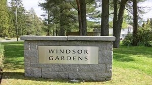 Een stenen bord met de tekst 'Windsor Gardens' in een park.