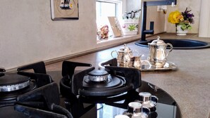 Un coin cuisine équipé d’une cuisinière à gaz, d’un évier et d’un plan de travail sur lequel se trouve un plateau avec une théière et des tasses.