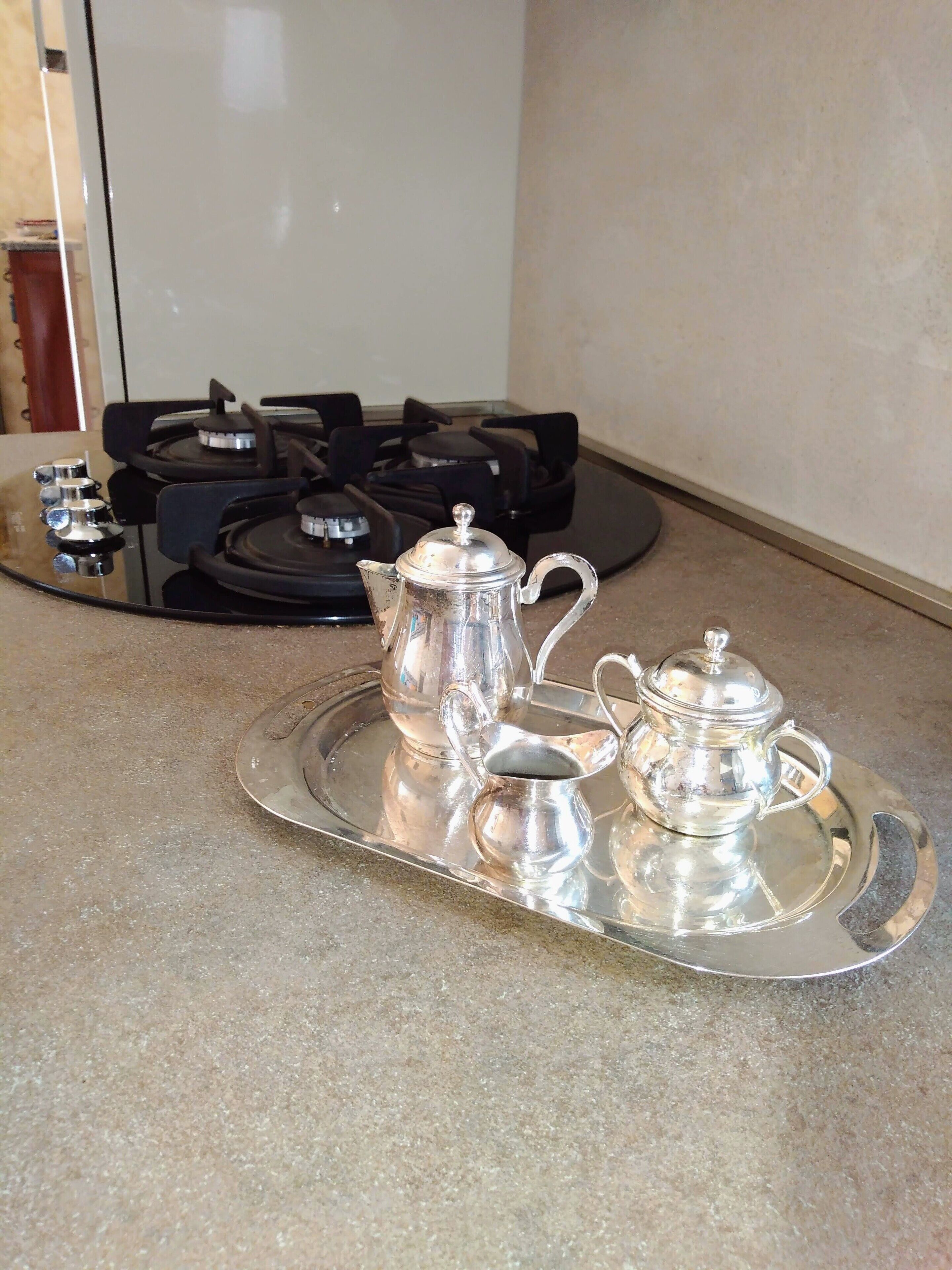 A kitchen with a gas stove and a tray with silver kitchenware.