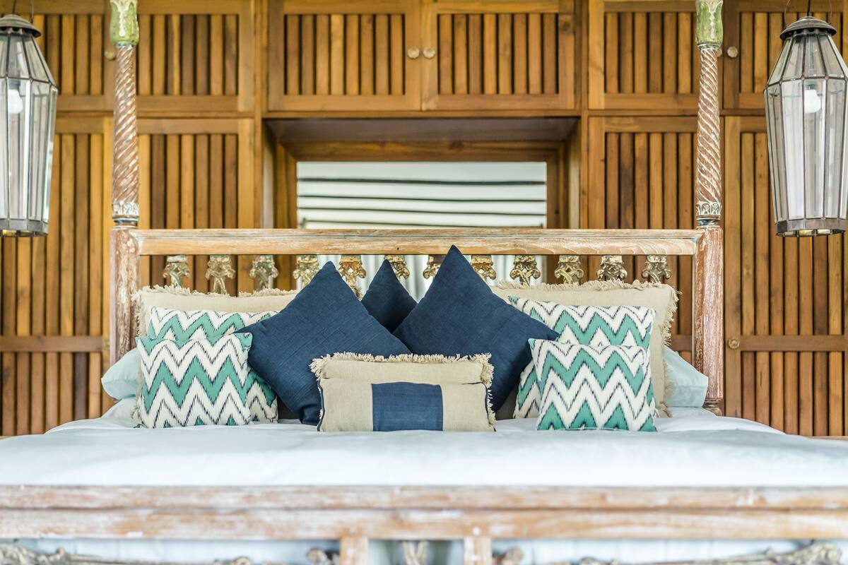A bed with a wooden headboard, multiple pillows, and two hanging lanterns.