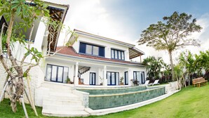 A two-story house with a swimming pool, a staircase leading to the entrance, and a well-maintained lawn. - Canggu Villa & Cooking Retreat (Tibubeneng)
