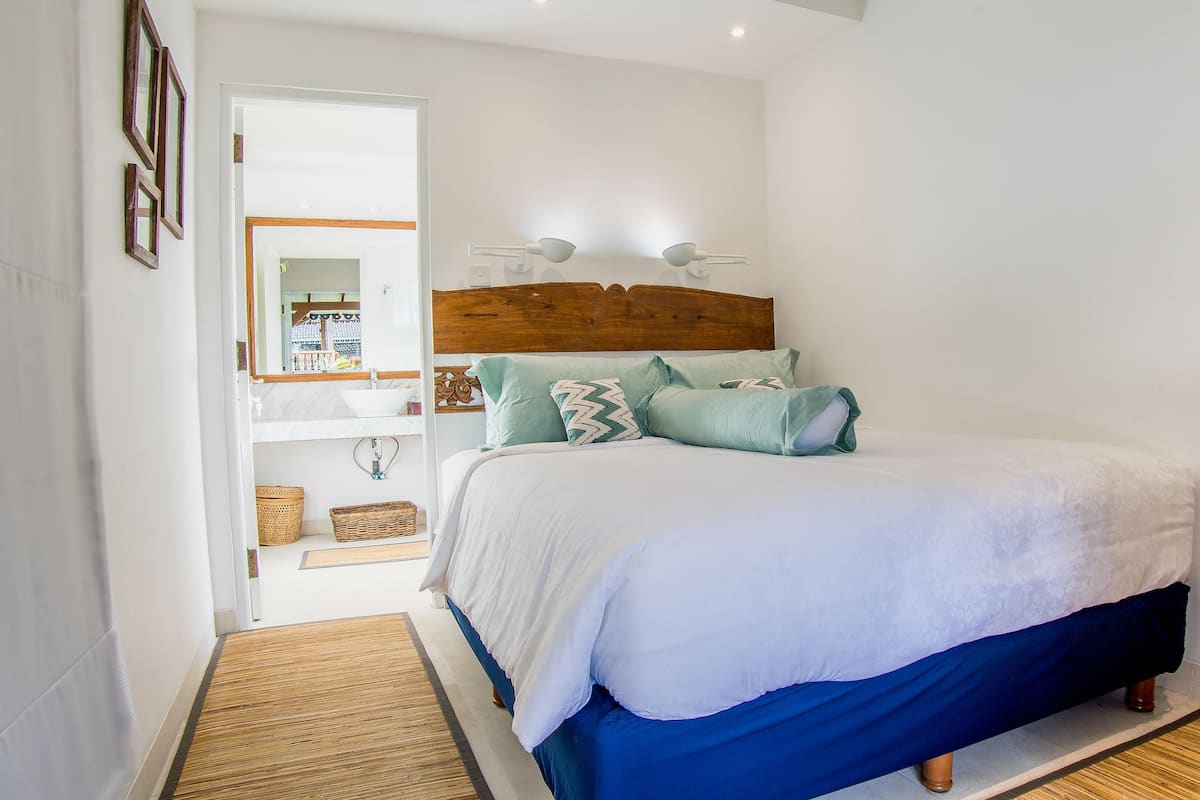 A bedroom with a wooden headboard, a white bedspread, and two wall-mounted reading lamps.
