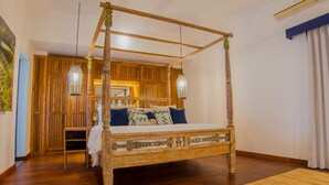 A four-poster bed with a wooden frame and a white bedspread, set in a room with wooden paneling and a large window. - Canggu Villa & Cooking Retreat (Tibubeneng)