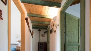 A narrow hallway with tiled flooring, wooden ceiling beams, and a green door on the right. - Villa Paradiso, in the beach by foot, big garden,  Wifi, all inclusive (Cala Liberotto)
