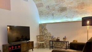 Un saló modern amb televisió plana, mobles de fusta, una paret decorativa de pedra i una làmpada.