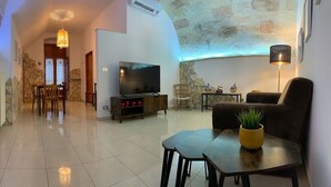 Un saló modern amb televisió, seients i una paret de pedra.