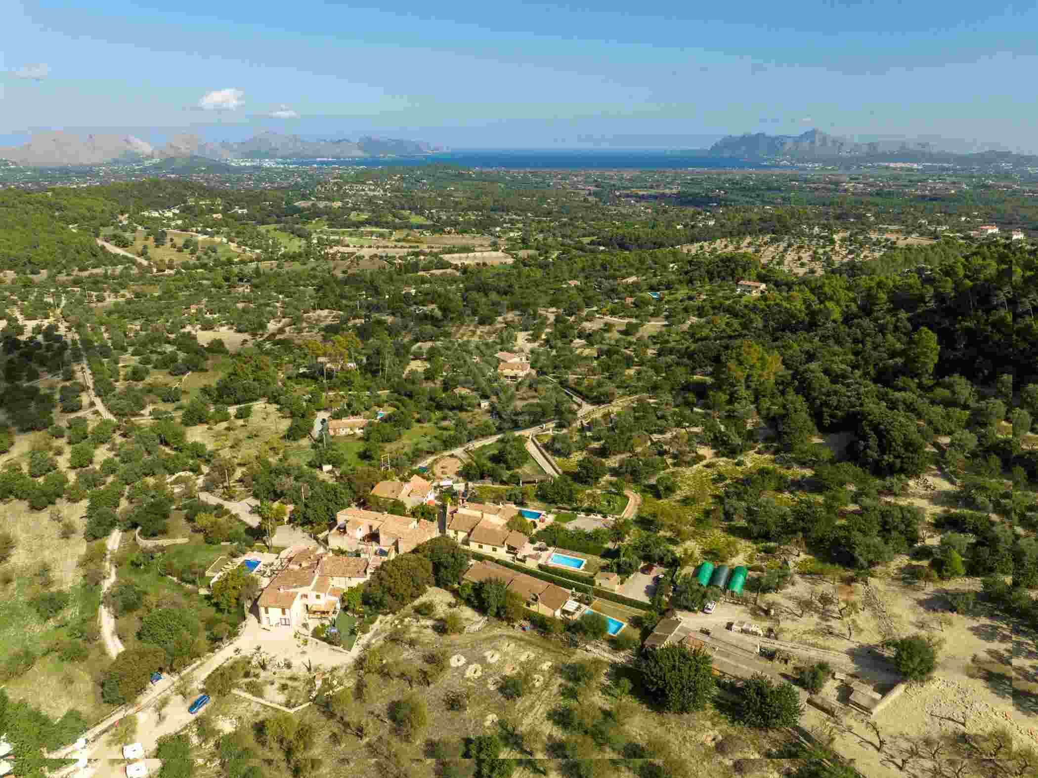 An aerial view of a residential area with houses, green spaces, and a swimming pool.