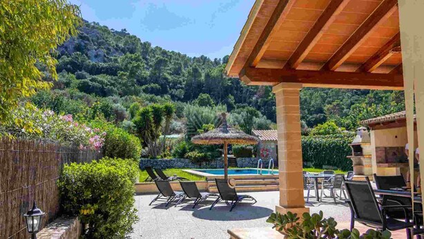 A covered outdoor area with a pool, lounge chairs, and a stone wall. - Can Bajoca 2 , beautiful peaceful surroundings (Pollensa)