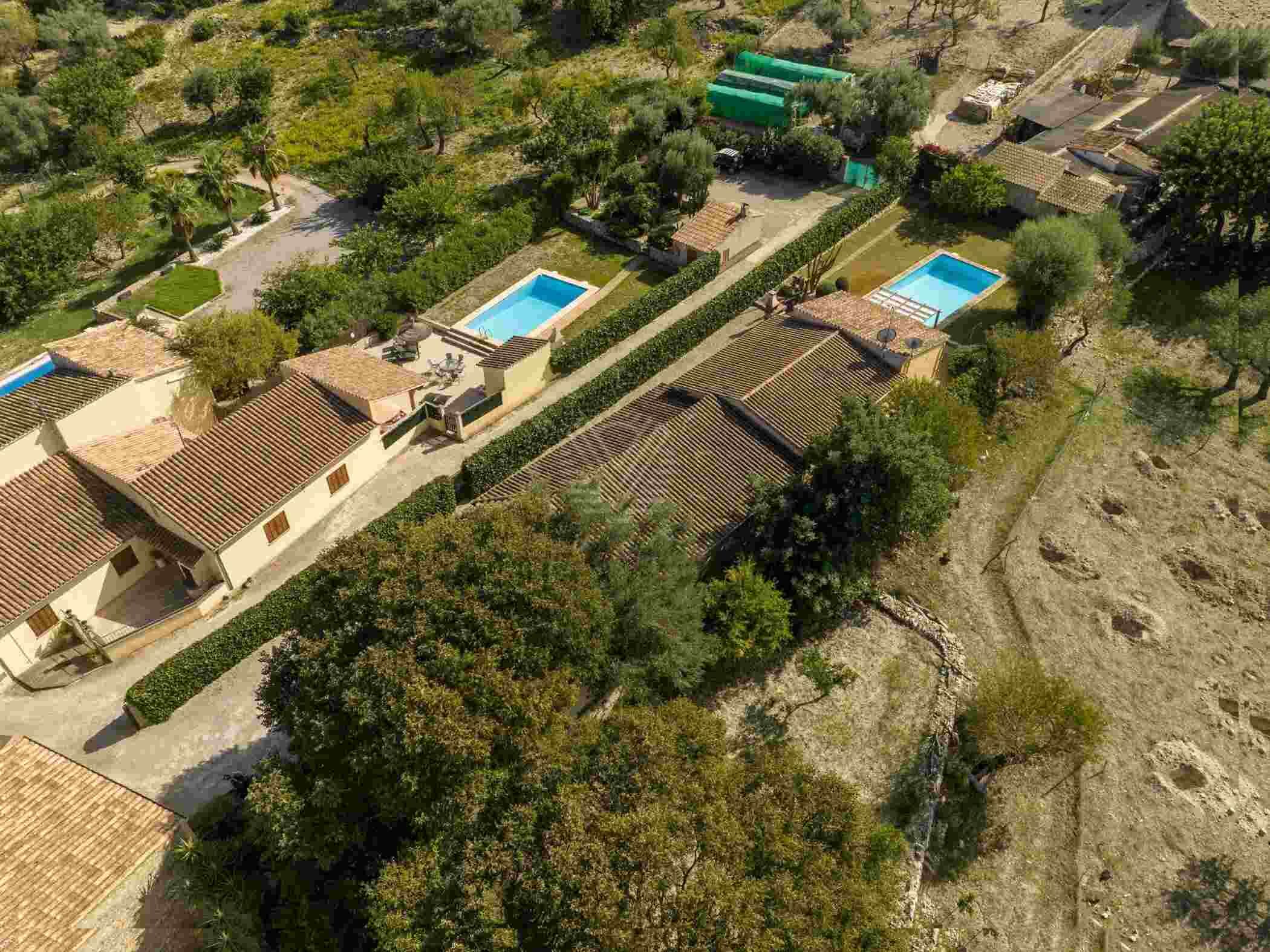 Vue aérienne d’un quartier résidentiel composé de plusieurs maisons, chacune ayant un toit en tuiles et une petite piscine.